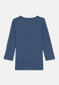 Camisola de manga longa azul com gola redonda e fendas laterais na barra. A textura é fina e trançada.