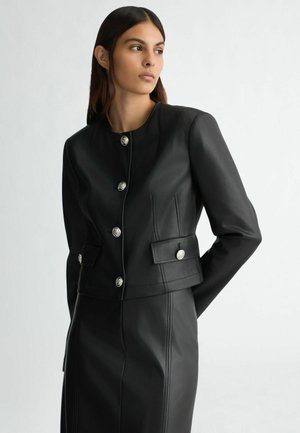 Black leather cropped jacket featuring round silver buttons, side pockets, and detailed stitching. Smooth texture with a structured fit.
