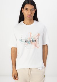 Biela bavlnená tričko s mnohobarebným geometrickým dizajnom; "LYLE AND SCOTT" vytlačené čiernou farbou; okrúhly výstrih; krátke rukávy.