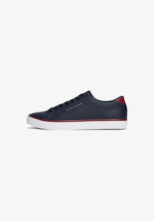 Sneaker in pelle blu navy con accenti rossi, suola bianca, lacci neri e marchio "Tommy Hilfiger" sul lato.