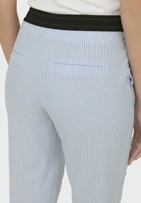 Blå och vitrandiga skräddarsydda byxor med svart elastiskt midjeband, featuring två bakfickor och en slim fit-design.