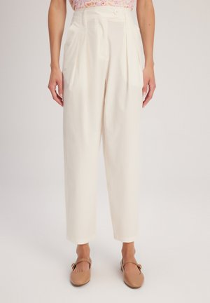 White high-waisted trousers with pleats, made of lightweight fabric. Features a front button closure and tapered legs.
