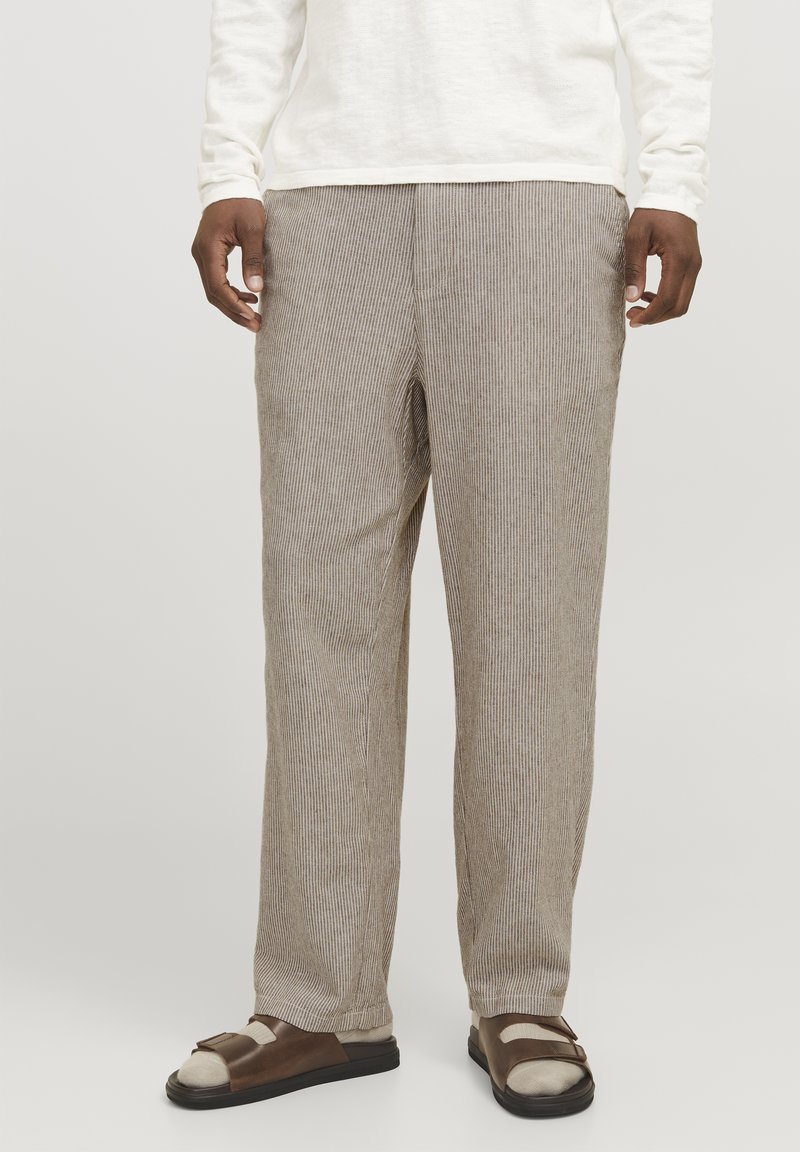 Beige gestreifte Hose mit entspannter Passform, die eine weiche Textur und einen geraden Schnitt aufweist. Getragen mit braunen Sandalen.