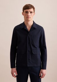 Giacca camicia blu navy realizzata in tessuto liscia, con colletto, chiusura a bottoni e due tasche frontali. Design semplice e strutturato.