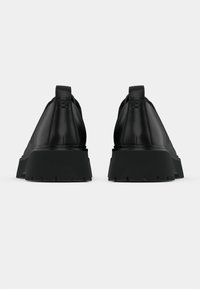 Juodi odiniai batai su apvaliu pirštu, pakeltu kulnu ir tekstūruota guma. Yra lygus viršus ir kilpa nugaroje.