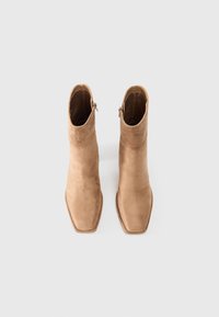 Suede ankle boots in light brown, featuring a square toe and a side zipper. Smooth texture and minimalistic design.