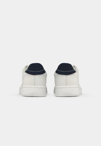 Pair of white sneakers with navy heel tabs and stitched details, viewed from the back on a white background.