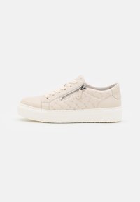 Beige lavtop sneaker med hvid sål, quiltet sidepanel, metal lynlåsdetalje og matchende beige snørebånd på hvid baggrund.