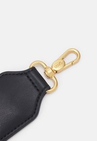 Lanière porte-clés en cuir noir avec mousqueton pivotant en métal doré gravé de "LIU JO" sur fond blanc.