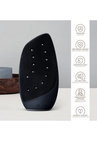 Svart silikon ansiktsrengöringsenhet med texturerad yta, med en formad design och upphöjda prickar, idealisk för alla hudtyper.