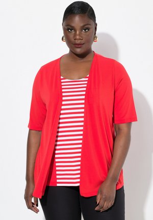 Cardigan leggero rosso sopra un top a righe bianche e rosse, indossato con pantaloni neri. Maniche corte e design aperto. Texture liscia.