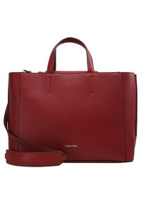 Sac à main en cuir rouge avec un design structuré, deux poignées, une bandoulière amovible et un détail en logo doré sur le devant.