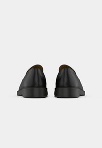 Sorte lærstøvler med en glatt tekstur, minimalistisk design og rund tå. Tykk svart gummisåle; ingen synlige detaljer eller mønstre.