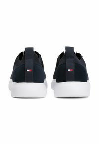Marine Sneakers mit strukturierter Oberseite, weißer Sohle und Zuglasche. Auf der Rückseite befindet sich ein kleines rot-weiß-blaues Logo.