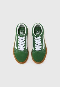 Grønne lerrets sneakers med hvite detaljer, som har hvite snøringer, rund tå og såle av gummigummi. Sømdetaljer langs sidene.