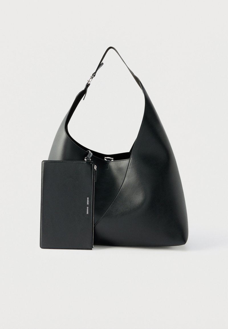 Sac à bandoulière en cuir noir avec une large sangle et une pochette zippée rectangulaire amovible attachée à l'avant.