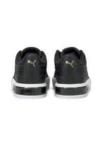 Svarta lädersneakers med vita sulor, med en glansig svart detalj och guld-logga på hälen. Rundad form med texturerad detalj.