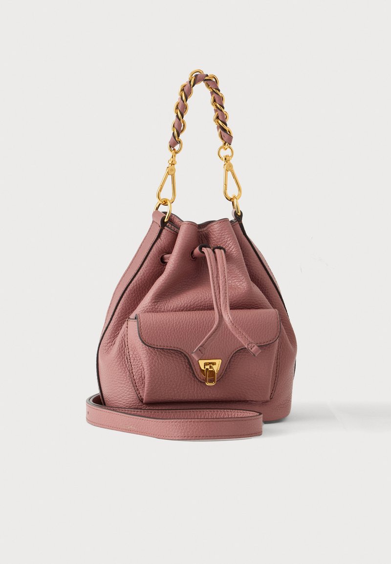 Sac seau en cuir mauve avec poche avant, fermoir doré, chaîne tressée et poignée en cuir, ainsi qu’une bandoulière ajustable assortie.