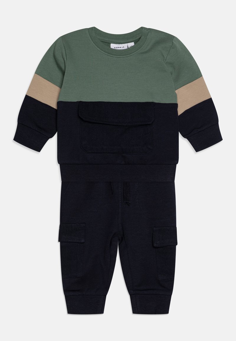 Dwu-elementowy zestaw dziecięcy składający się z zielono-beżowej, kolorowej bluzki z kieszonką oraz granatowych spodni z kieszeniami cargo i elastycznymi mankietami.