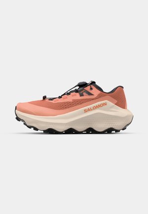 Chaussure de trail running en corail et crème, avec un dessus texturé, des accents noirs, un système de laçage rapide et une semelle épaisse et profilée pour une meilleure traction.