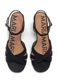 Sandalias de ante negro con diseño de tiras entrecruzadas, correa con hebilla en el tobillo y plantilla acolchada marrón con marca visible.