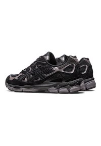 Paire de chaussures de course athlétiques noires et gris foncé avec des détails en mesh et en suède, semelles épaisses et rembourrées, et logo de marque visible sur les côtés.