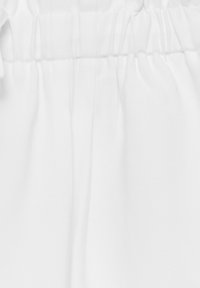 Biała tkanina o miękkiej, gładkiej teksturze, z zebranym elastycznym paskiem w talii. Prosty design bez wzorów czy akcentów.