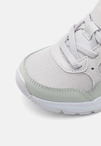 Basket en gris clair avec des panneaux en maille et en cuir, tige texturée, bout rond et lacets plats, avec un accent vert menthe près de la semelle.