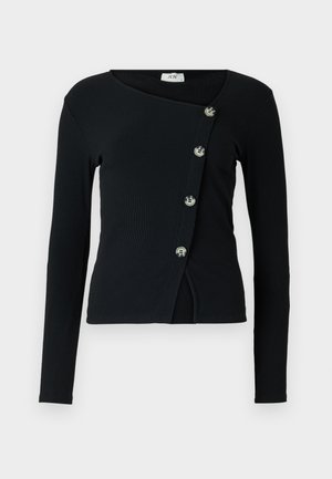 Sort langærmet top med ribbet tekstur og asymmetrisk design. Har knapper langs forsiden til lukning og en tætsiddende silhuet.
