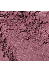 Poudre mauve-violette écrasée et scintillante, à la texture rugueuse, probablement un fard à paupières ou un produit de maquillage, étalée de manière irrégulière à la surface.
