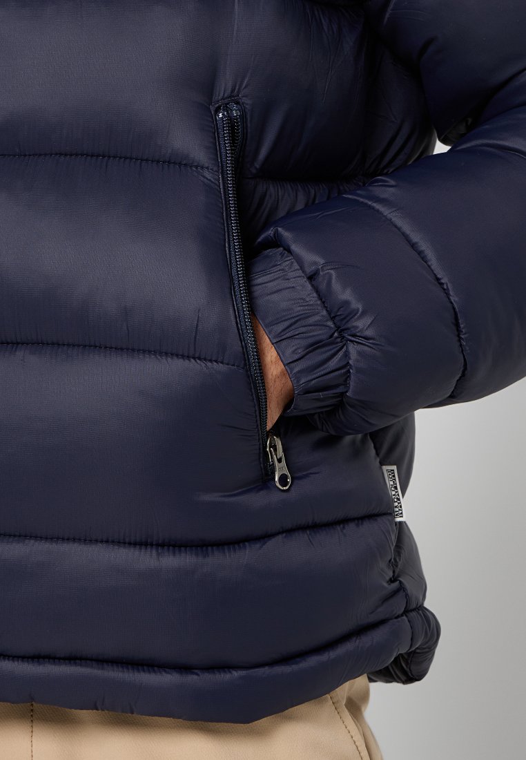 Navyblauer Puffer-Jacke mit horizontalem Steppmuster, ausgestattet mit einer mit Reißverschluss versehenen Seitentasche und elastischen Bündchen für Wärme und Komfort.