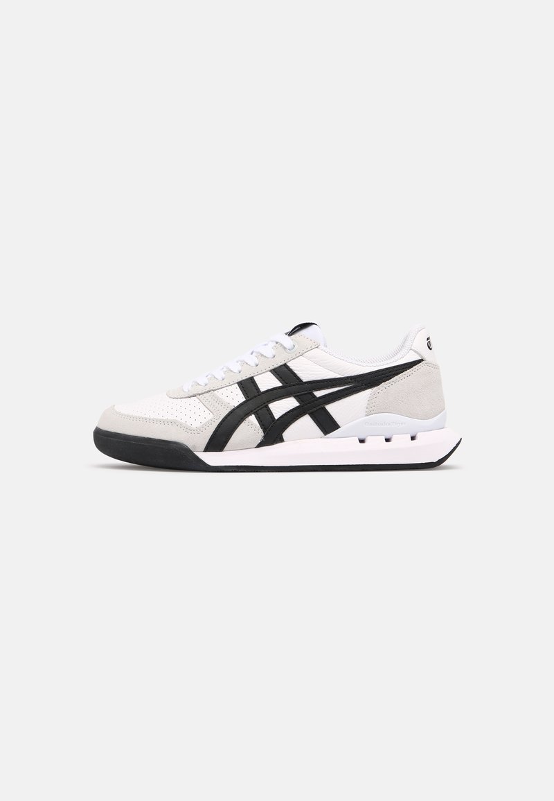 Athletic shoes with a white leather and gray suede upper, featuring black stripes, a thick rubber sole, and lace-up design.