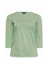 Ljusgrön långärmad skjorta med rundad halsringning, knappslå och vertikala veck fram. Mjuk, texturerad tyg.