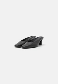 Mule-uri din piele neagră cu un design cu vârf punctat, toc mic și stil slip-on. Textură netedă și construcție minimalistă.