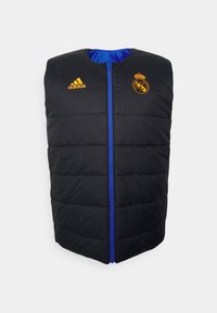 Mustat toppaliivi, jossa on sininen vetoketju, oranssi Adidas-logo ja Real Madrid -logo vasemmassa rinnassa, kaareva kaula-aukko ja hihaton muotoilu.