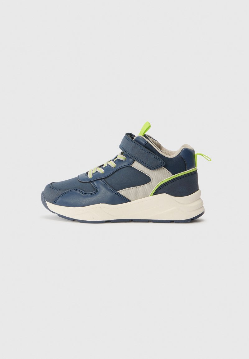 Sneaker blu navy con accenti grigio chiaro, fascia in velcro, tomaia testurizzata e linguetta verde sul tallone. Suola spessa per supporto e trazione.