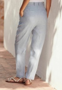 Pantalons bleu clair à coupe droite, en tissu texturé. Deux poches arrière et des poches sur les coutures latérales. Associés à des sandales à lanières brunes.