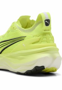Scarpa da corsa gialla neon con tomaia in mesh traspirante, strisce laterali nere e una spessa suola intermedia bianca. Presenta il logo Puma sul tallone e sulla linguetta.