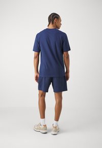 T-shirt in cotone blu navy a maniche corte, abbinato a pantaloni corti coordinati. Tessuto liscio, vestibilità comoda, design semplice senza fantasia.