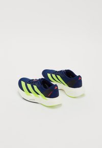 Adidași de alergare albaștri cu dungi verzi neon, accente negre și o talpă albă cu partea de jos verde; design ușor din material mesh.