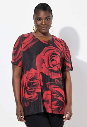 Top nero con grande stampa di rose rosse, maniche corte, scollo rotondo, tessuto trasparente e orlo ondulato. Abbinato a pantaloni neri.