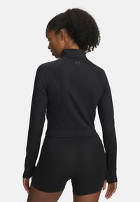 Black athletic long-sleeve top with a high collar and ribbed texture, paired with black shorts, featuring a fitted design and smooth fabric.