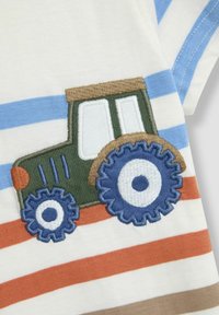 Baumwollhemd mit blauen und orangefarbenen Streifen, versehen mit einem grünen, gestickten Traktormotiv und blauen Zahnrädern.