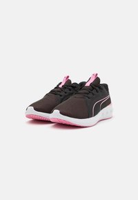 Baskets de sport noires en tissu en maille, avec des accents roses et des semelles blanches présentant un motif de traction texturé. Équipées de lacets et d'une languette.