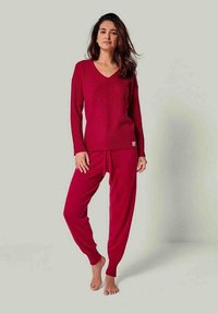 Rotes Strick-Loungewear-Set mit einem langärmeligen V-Ausschnitt-Oberteil mit geripptem Textur und lockeren Hosen mit elastischem Bund, in einfarbigem Design.