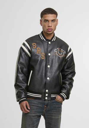 Black leather varsity jacket with white stripes and brown embroidered details. Features snap buttons, ribbed cuffs, and side pockets.