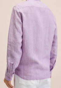 Chemise à manches longues couleur violet clair en lin, dotée d'un poignet boutonné et d'un col classique. Tissu texturé avec une apparence légèrement délavée.