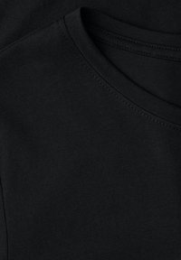 Czarna bawełna z okrągłym dekoltem, o gładkiej fakturze i płaskich szwach, starannie ułożona na identycznej warstwie.