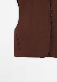 Brun, texturerad väst med välvd fåll, som har svarta knappar framtill och sidofickor. Materialet verkar robust och vävt.