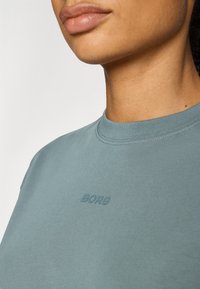 Svijetloplava kratkotrajna košulja od mekanog pamuka, s okruglim izrezom i suptilnim reljefnim logom "BORG" na prednjoj strani.